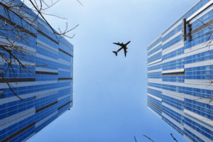 avião voando entre prédios