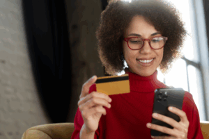 Mulher com celular e cartão de crédito