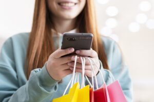 mulher com sacola de compras e celular