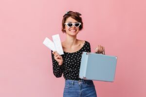 mulher com passagens e mala de viagem