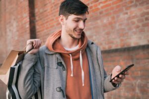 homem com compras e celular