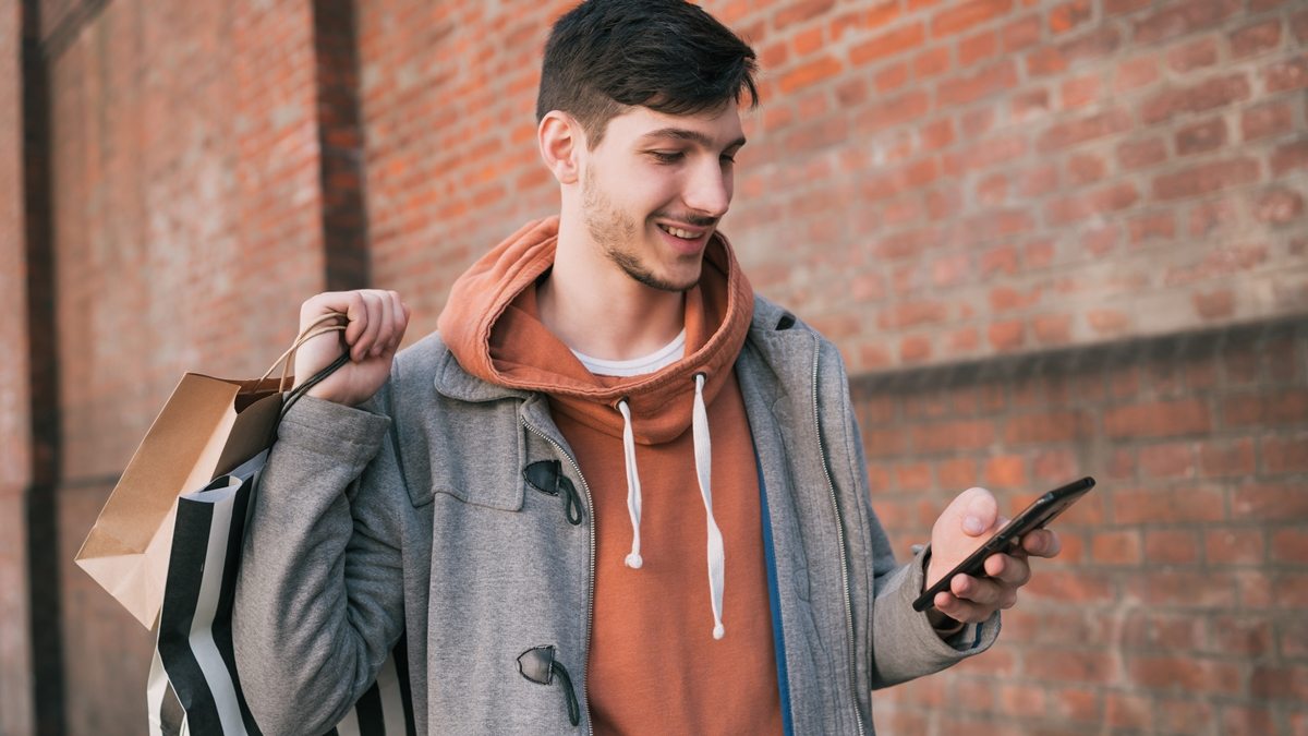 homem com compras e celular
