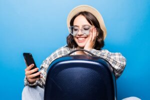 mulher com celular e mala de viagem