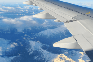 Avião comercial em voo sobre montanhas com paisagem de inverno