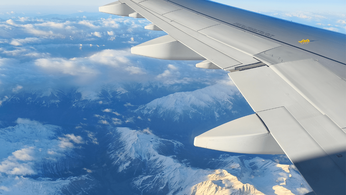 Avião comercial em voo sobre montanhas com paisagem de inverno