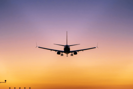 Avião comercial se aproximando para pouso ao entardecer.