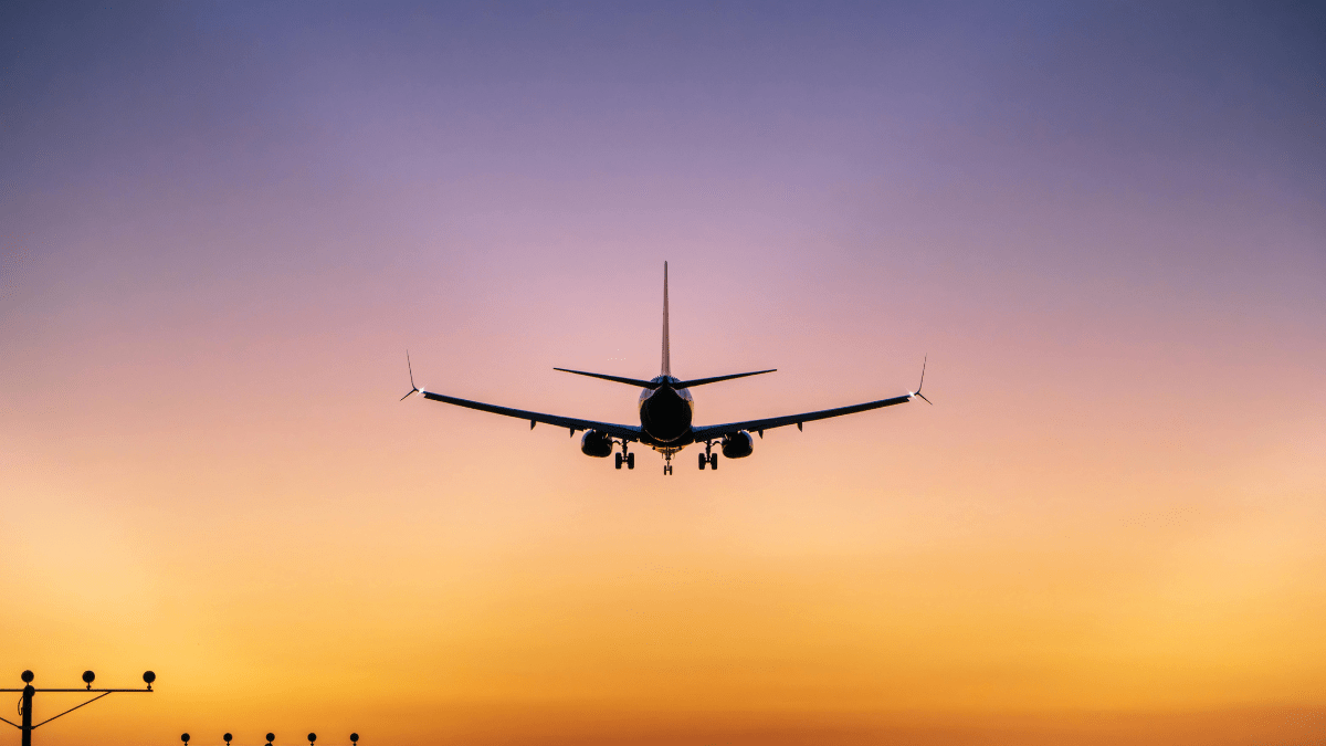 Avião comercial se aproximando para pouso ao entardecer.
