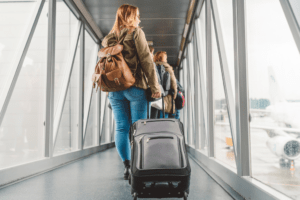 Passageira caminhando pelo finger do aeroporto com mala de rodinhas em direção ao embarque