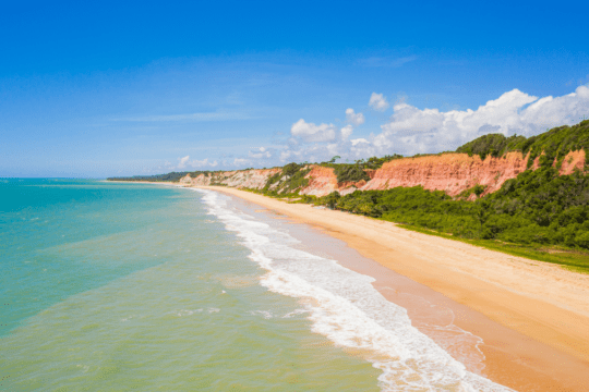 Vista aérea da praia em Porto Seguro com falésias, mar azul e faixa de areia clara