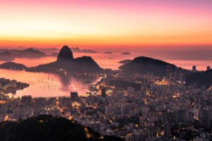 Vista aérea do Rio de Janeiro ao entardecer, com o Pão de Açúcar e a Baía de Guanabara