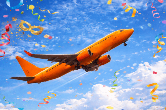 Avião comercial decolando em céu azul com confetes de carnaval coloridos ao redor