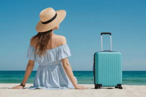 Mulher na praia com mala de viagem azul
