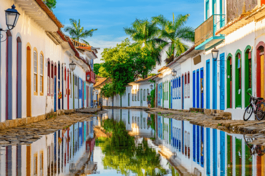 Rua histórica de Paraty com casarões coloniais coloridos refletidos na água após a maré subir no centro histórico.