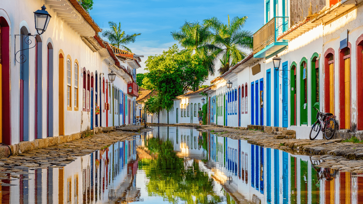 Rua histórica de Paraty com casarões coloniais coloridos refletidos na água após a maré subir no centro histórico.