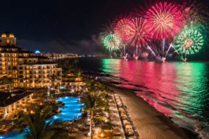 Resort à beira-mar em praia brasileira durante o réveillon com fogos de artifício coloridos sobre o mar à noite